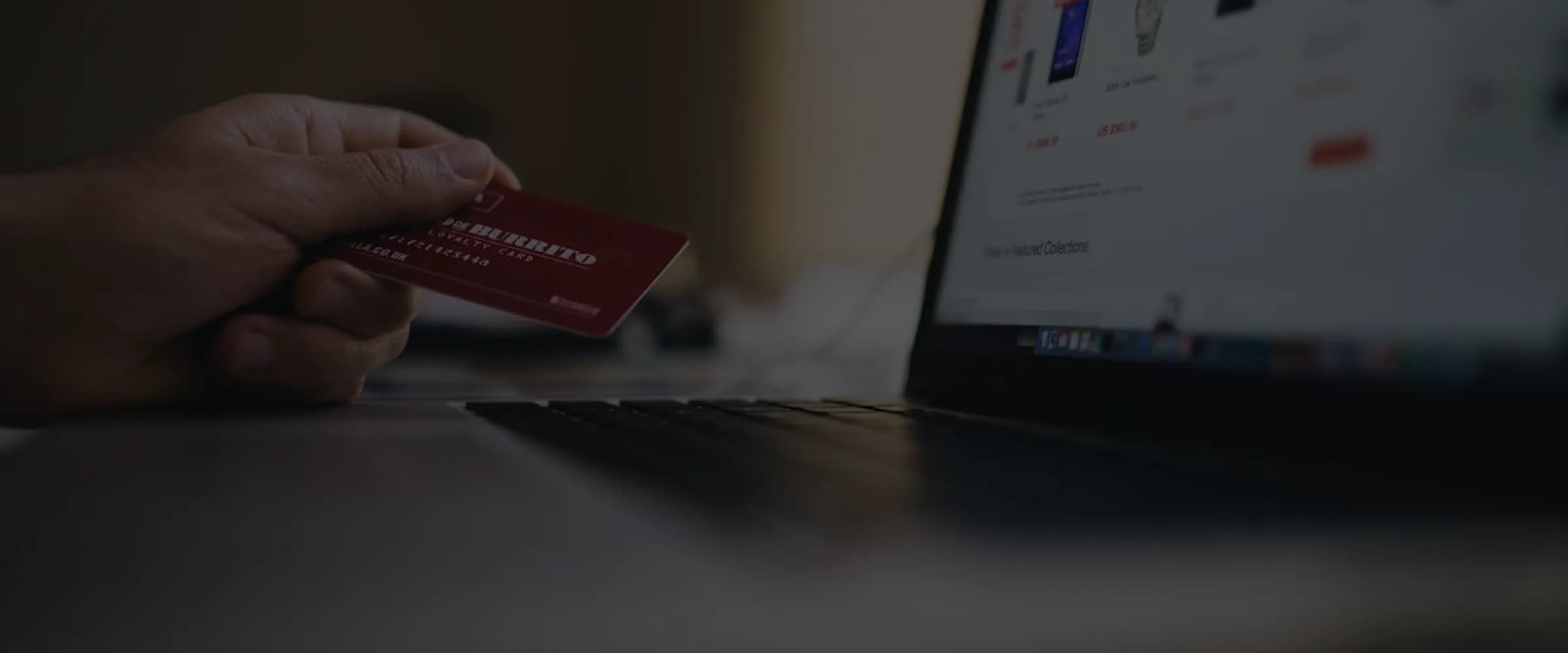 Customer holding a credit card while making an online purchase on a laptop