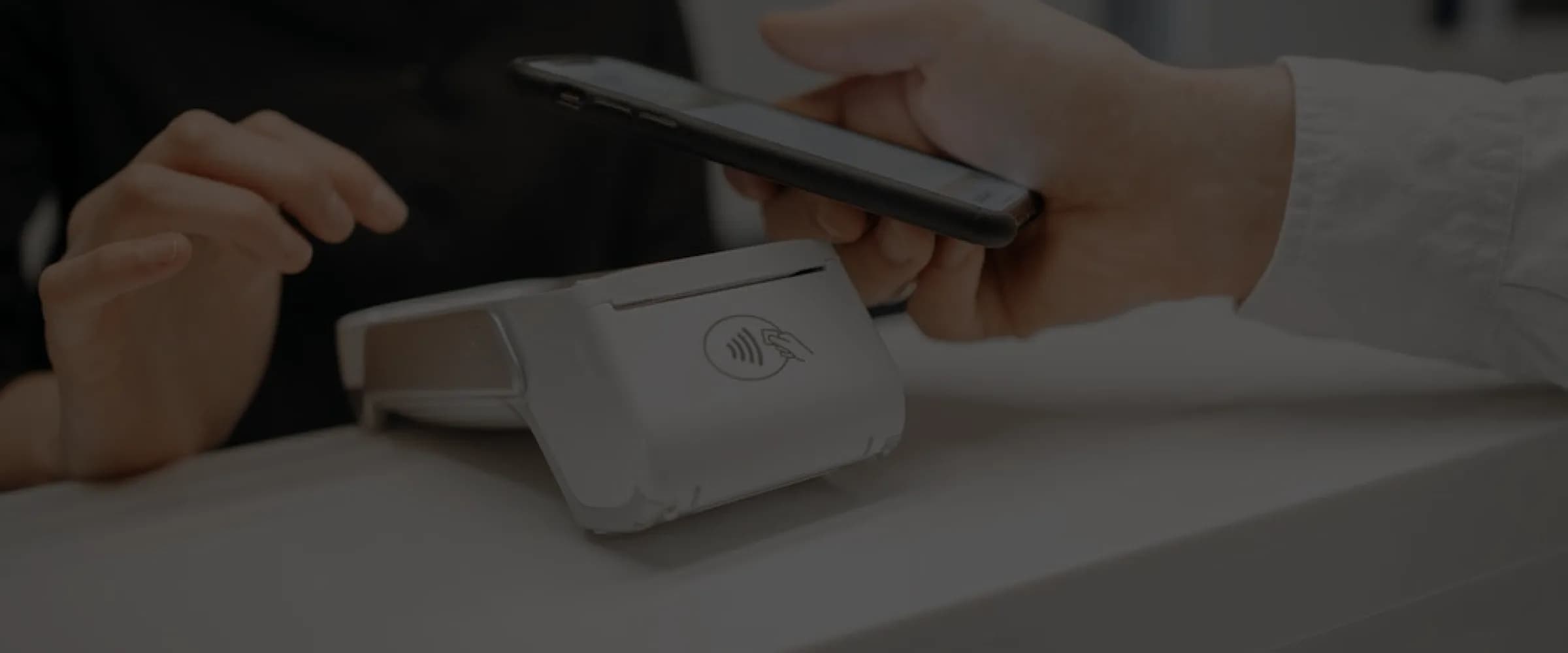 Customer using a smartphone to make a contactless payment on a POS terminal