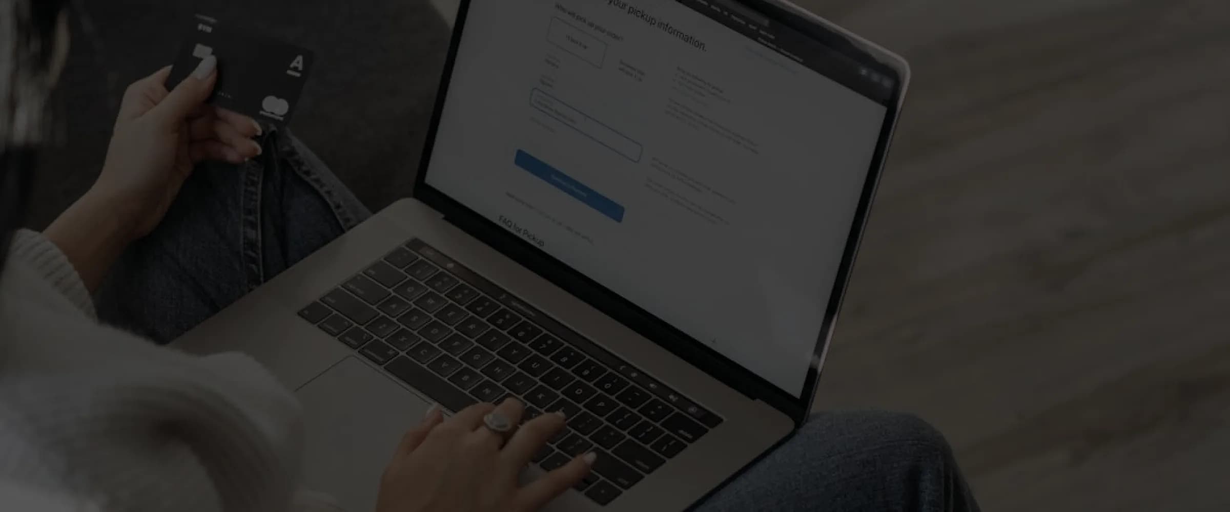 Customer holding a credit card while completing an online checkout on a laptop